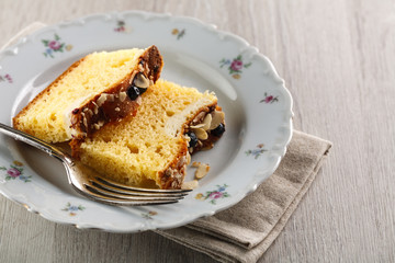 sliced cake with almonds and blueberries on a white ceramic plate