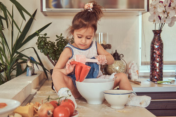 Sweet little cute girl learns to cook a meal in the kitchen.