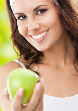 Woman in fitness wear with apple, outdoors