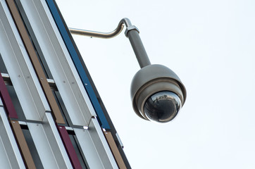 Fototapeta na wymiar closeup of security camera on modern building on grey sky background