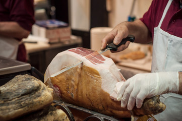 closeup of man cutting smoked ham at the market