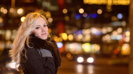 Beautiful, blonde woman in car lights in the night city.
