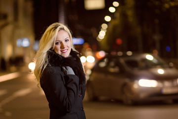 Fototapeta premium Beautiful, blonde woman in car lights in the night city.