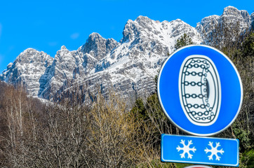 A view of the snow-capped peak of Monte Resegone, with a mandatory snow chain road sign in the...