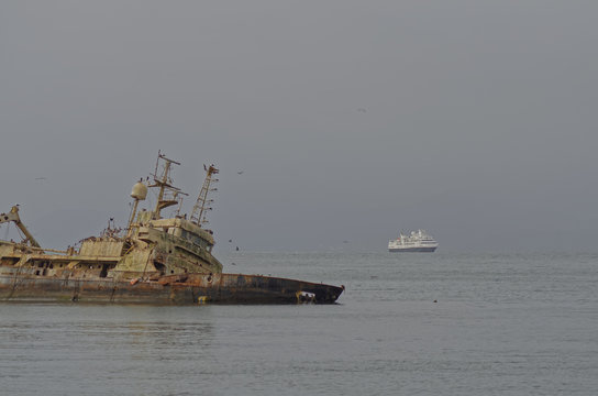 Sunken ship on the coast of Coquimbo, with birds nesting inside it, and in the background a cruise ship entering