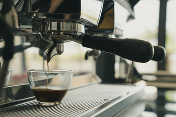 Close-up of espresso pouring from coffee machine. Professional coffee brewing, Barista Cafe making coffee preparation service concept, Vintage tone