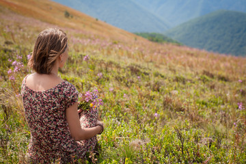 woman in summer dress with flowers enjoying mountain view. vacation and relaxation, silence