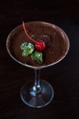 Ice cream chocolate dessert decorated with cherry on dark brown background