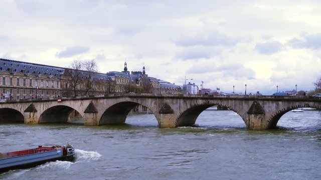 barge floating by the Seine river under the bridge at Paris