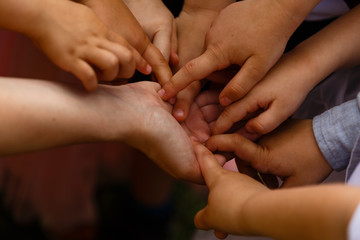 Close-up of many children's hands holding together as a team on a nature background