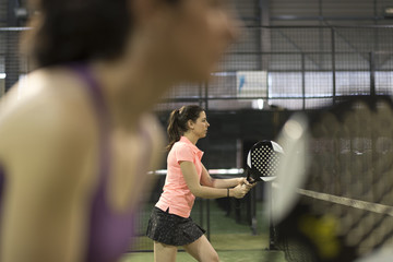 cpouple of women playing paddle tennis in indoor court
