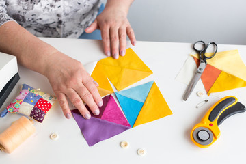 quilting, profession, equipment concept. top view of table with tools for sewing such as scissors and pillow for needles, they are placed around patches in different coloures