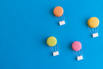 Hot air balloons made of macarons isolated on blue, abstract concept.