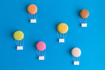 Hot air balloons made of macarons isolated on blue, abstract concept.