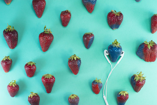 A strawberry is lisetening to music through earphone... And music is contagious.