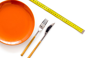 Diet for weight loss concept. Proper nutrition. Medical starvation. Empty plate with fork and knife near measuring tape on white background top view mockup