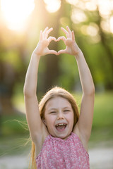 Pretty little girl shows heart shaped gesture