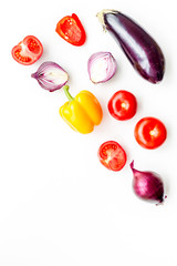 Layout of contrast, colored vegetables. Eggplant, red onion, red pepper, tomato on white background top view copy space pattern