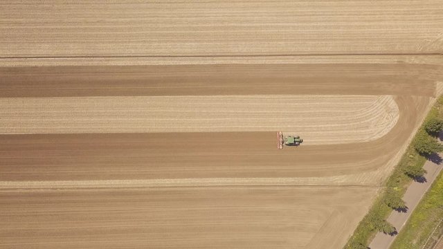 Trattore verde sta arando il terreno per la semina del grano. Vista aerea