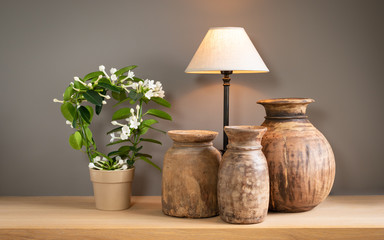 Decorative living room still life with lamp, flowering plant and old cute wooden jugs. Home interior concept.