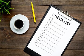 Blank checklist with space for ticks on pad on office desk. Checklist for office worker, manager, businessman, chief on dark wooden background top view