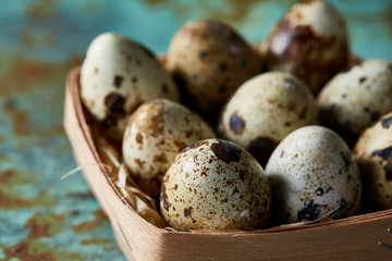 Quail eggs in a box on a blue textured background, top view, selective focus.