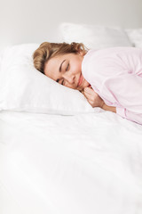 Portrait of beautiful smiling lady in pink pajamas sleeping in bed at home isolated