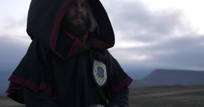 The knight looks arrogantly His head covered by hood Wind blow