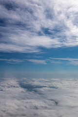 View from the airplane to the sky above the Alps mountains. Blue sky with clouds. Background.