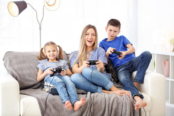 Young woman playing video games with her children at home