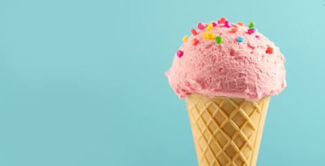 Ice cream. Strawberry or raspberry flavor icecream in waffle cone over blue background. Sweet...