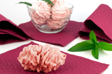 Pink home-made marshmallows with mint leaves and burgundy napkins.