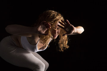 Mujer joven realizando danza contemporánea en estudio con fondo negro 