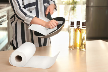 Woman wiping frying pan with paper towel indoors