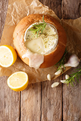 Fondue in a loaf of bread from melted camembert cheese close-up. Vertical top view