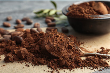 Spoon and pile of cocoa powder on table