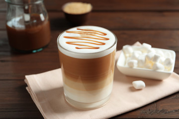 Glass with delicious caramel latte on table
