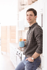 Portrait of confident young man with cup in kitchen