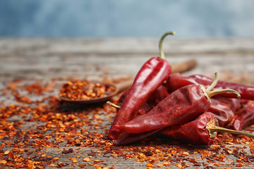 Dry chili peppers and powder on wooden table