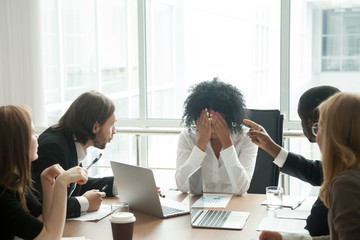 Rude diverse colleagues humiliating offending stressed upset young african woman leader suffering from gender racial discrimination during meeting or feeling exhausted tired of responsibility at work - obrazy, fototapety, plakaty