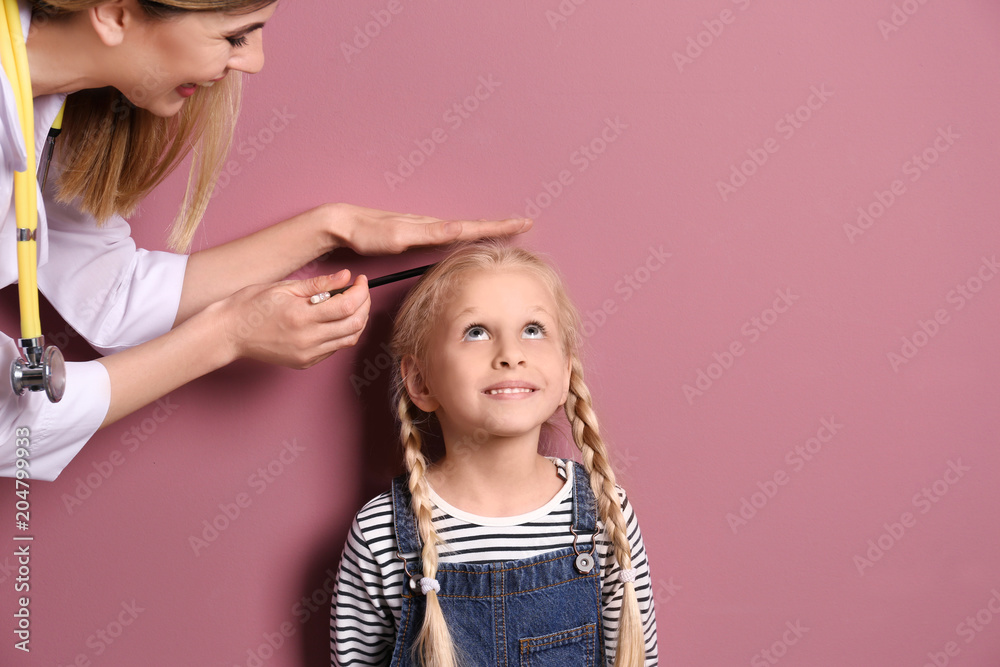 Wall mural Doctor measuring little girl's height on color background