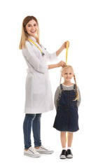 Doctor measuring little girl's height on white background