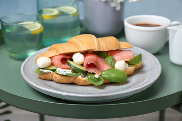 Plate with tasty croissant sandwich on table