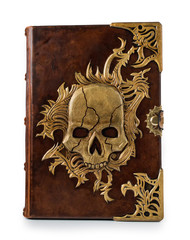 Brown leather book with the large gilded skull implemented into the front cover plate. Isolated the book staying to the table captured frontal.