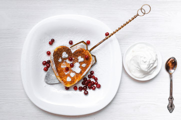 Freshly baked curd on the plate with cranberry and powdered sugar and sour cream on white wooden table background.