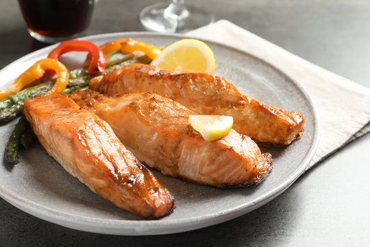 Tasty cooked salmon with vegetables on plate, closeup