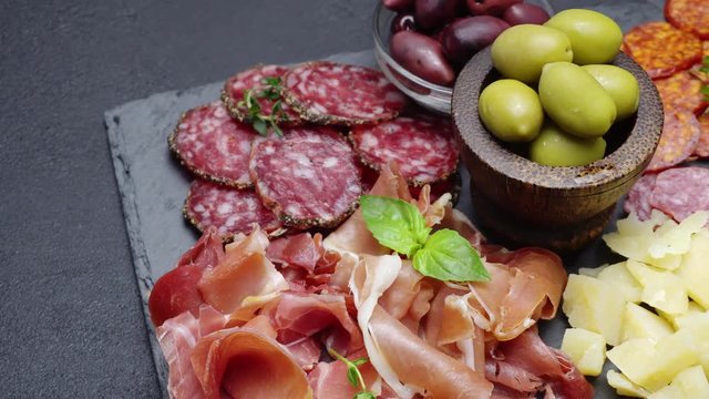 sliced prosciutto, cheese and salami sausage on stone serving board