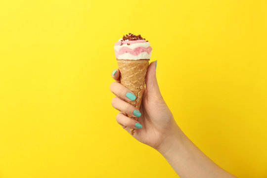 Woman holding yummy ice cream on color background. Focus on hand
