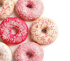 Delicious glazed doughnuts with sprinkles on light background, top view