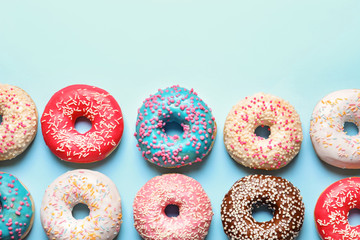 Delicious glazed doughnuts on color background, top view